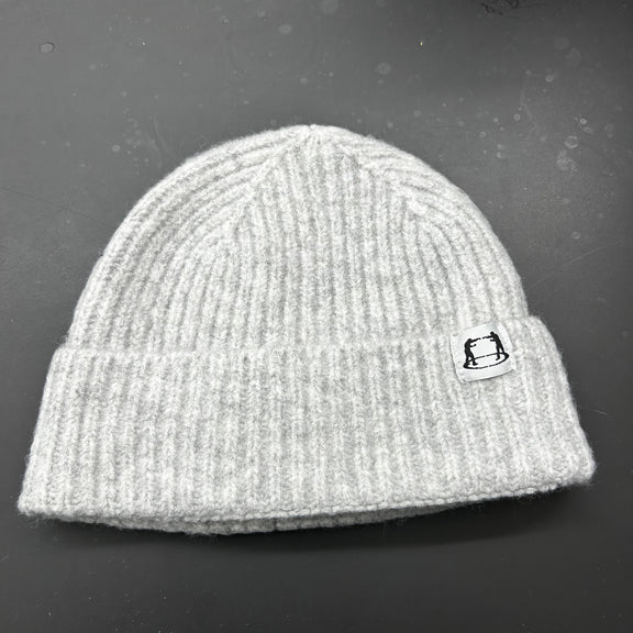 Gray knit beanie with a small logo on a dark surface