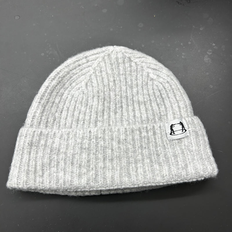Gray knit beanie with a small logo on a dark surface